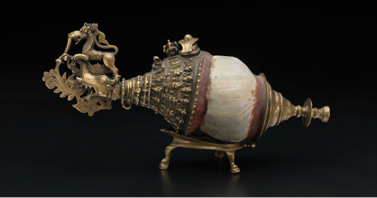– Shankha ou trombeta de concha com bocal e detalhes de latão e cera O instrumento é associado ao deus Vishnu mas a decoração na concha permite sua ligação aos rituais do shivaísmo.